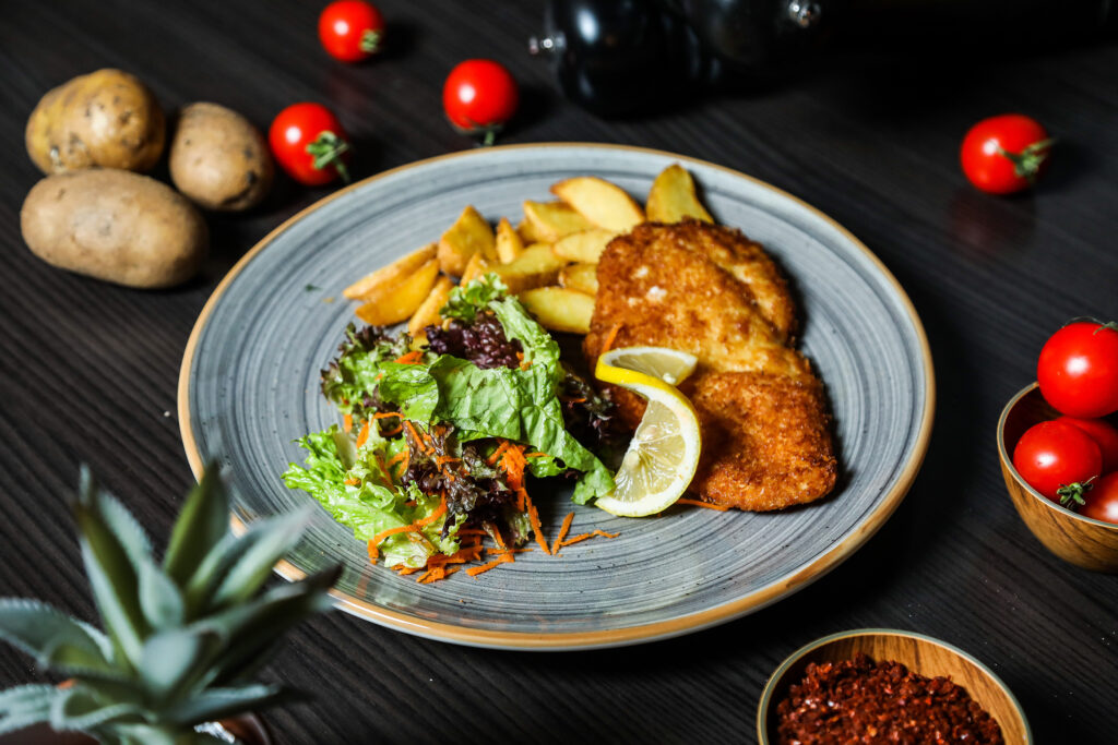 Teller in einem Restaurant mit Schnitzel, Pommes und Salat